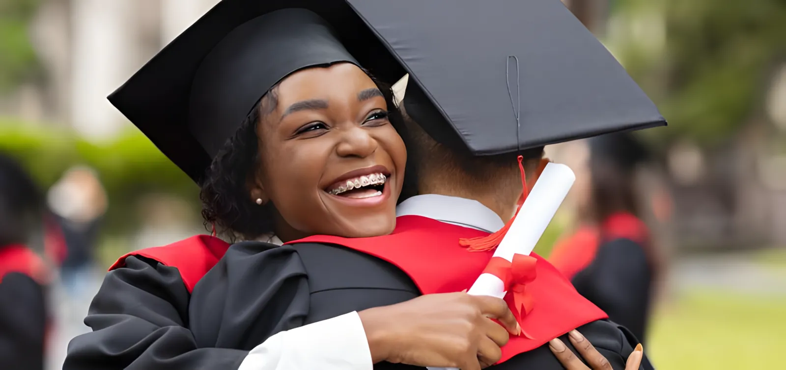 Jeune diplômée en toge, rayonnante, serrant un proche dans ses bras le jour de la remise des diplômes